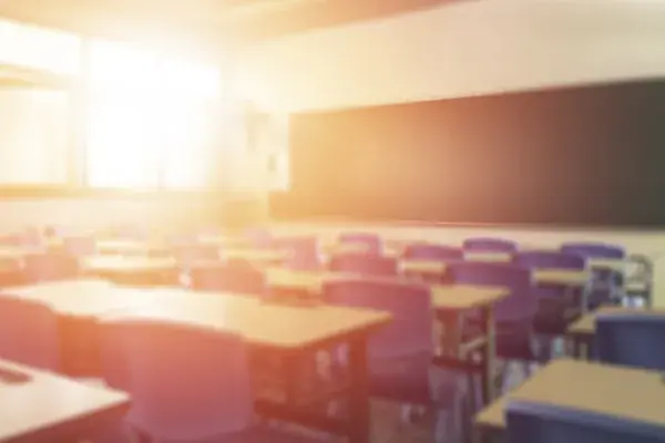 an empty classroom with a bright beam of light coming in from the windows on the left side of the room