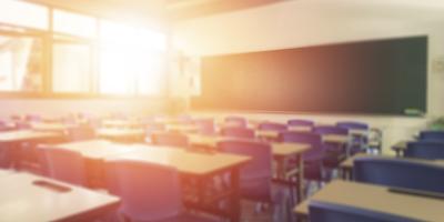 an empty classroom with a bright beam of light coming in from the windows on the left side of the room