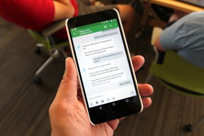 The Evorus chatbot uses humans not only to augment AI, but also to simultaneously train it — gradually reducing the chatbot's dependence on people. a hand holding a mobile phone with the Evorus chat window open