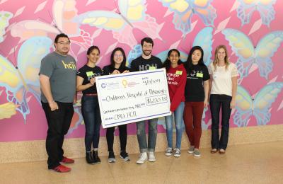 six people from CMU MHCI stand with rep from UPMC Foundation for check presentation at UPMC Children's Hospital