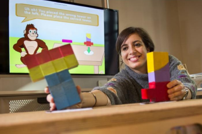 Nesra sits at a NoRILLA table and reaches for a tower of blocks