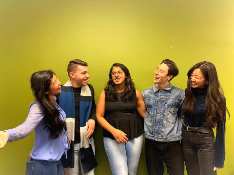 5 team members stand in front of the MHCI green wall