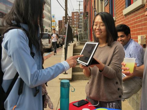 female student pays via POS tablet during a user testing session at a pop up lemonade stand on Craig St 