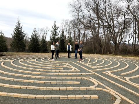 5 students on team Boulder Crest stand in the center of an outdoor labrynth