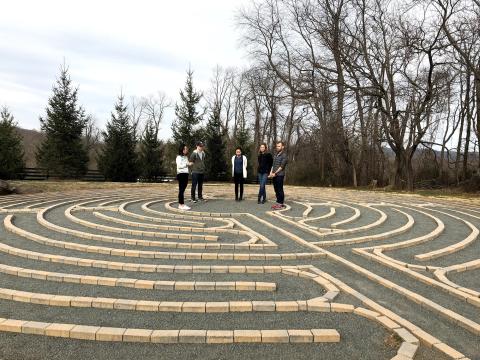 5 students on team Boulder Crest stand in the center of an outdoor labrynth 