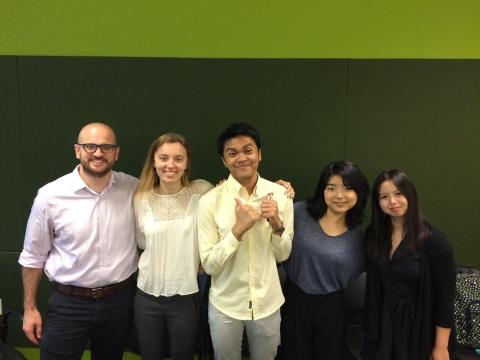 5 team members stand side by side in front of green background