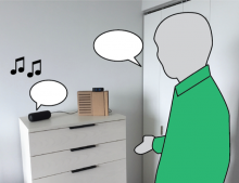 silhouette of a man in a green shirt standing beside DJ bot, which sits on top of a dresser in his home