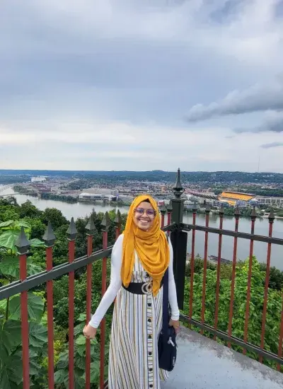 Photo of PhD Student Faria Huq on an overlook in front of a river