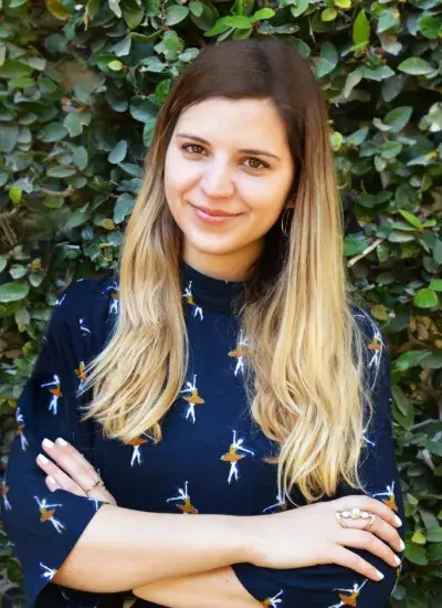 Photo of Michal Luria in front of green foliage