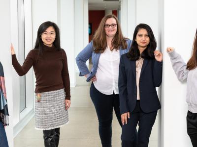 Five female AI researchers stand in the bridge between NSH and Gates 