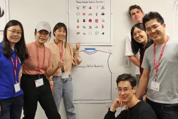 seven students gather around their winning tshirt design sketch during the orientation competition