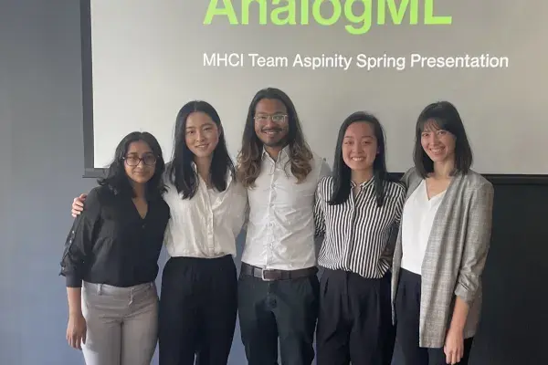 5 team members stand side by side in front of projector screen 