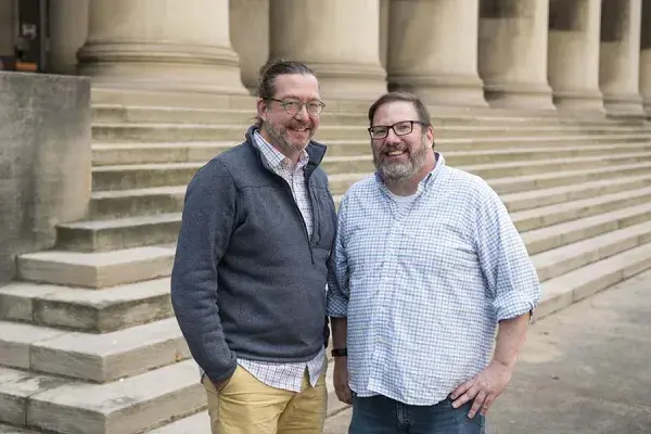 Norman Bier and John Stamper stand on the concrete steps in front of the CMU Mellon College of Science building