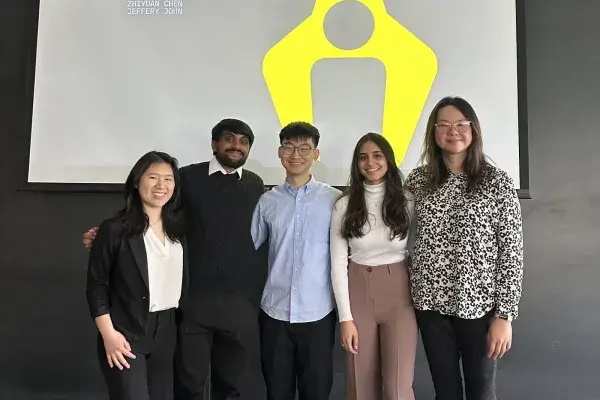 Team MHCI x ARM Institute stands side by side at the front of a classroom on presentation day