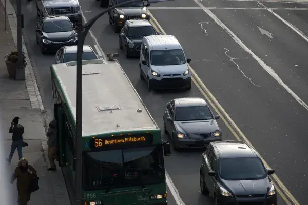 aerial shot of a sidewalk, bus stop and street with 2 lanes of traffic