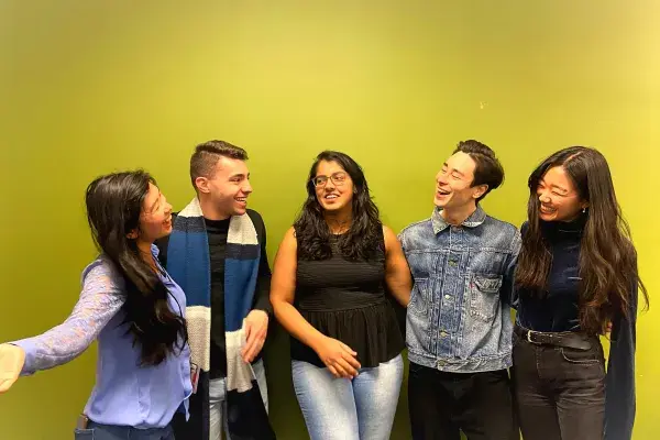 5 team members stand in front of the MHCI green wall