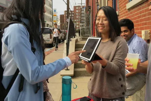 female student pays via POS tablet during a user testing session at a pop up lemonade stand on Craig St 