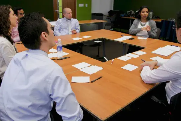 6 team members sit around 4 tables arranged in a square formation