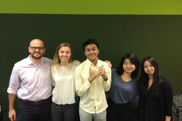 5 team members stand side by side in front of green background