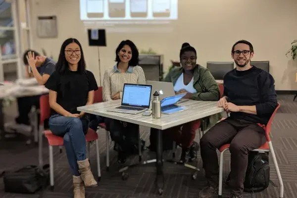 the four team members sit around a square table in the HCII lobby