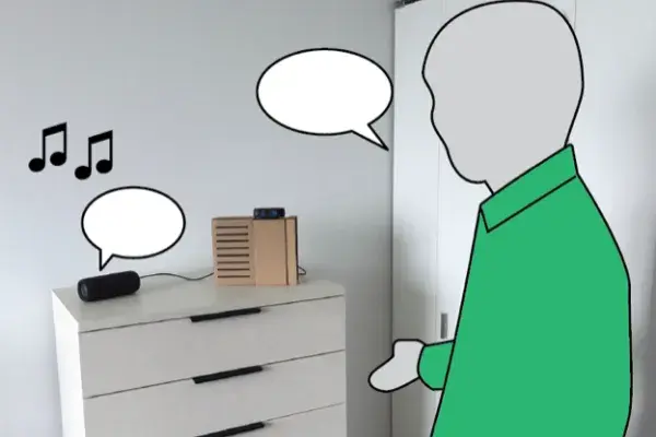 man in a green shirt standing beside DJ bot, which sits on top of a dresser in his home