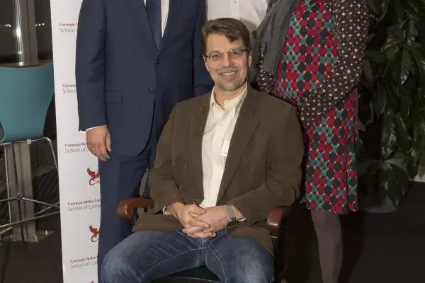 Ken Koedinger is seated in Hillman Professorship chair, while interim CMU president, dean of SCS, and director of HCII stand behind him